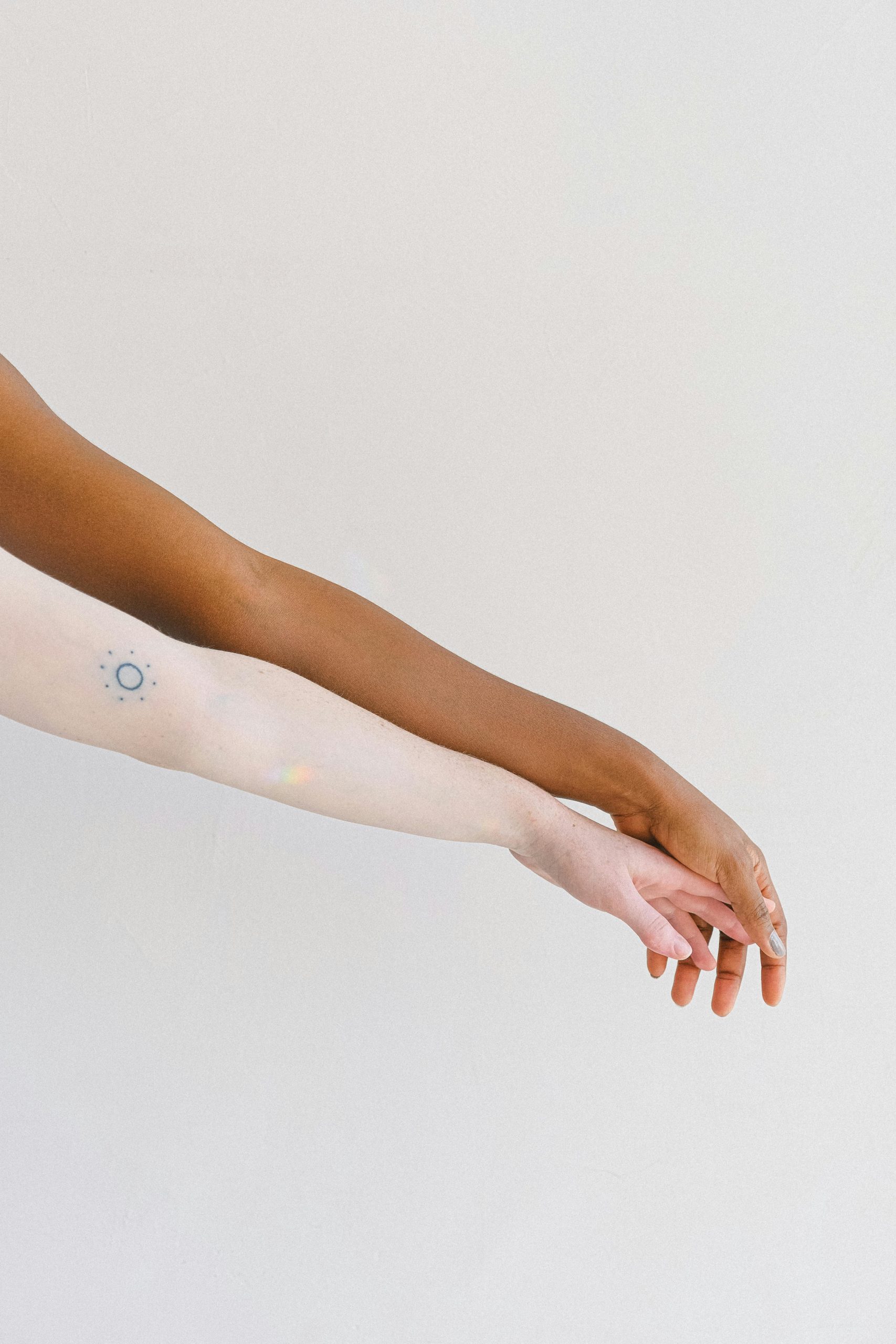 Deux bras de tons de peau différents affichés sur un fond blanc, l'un avec un tatouage