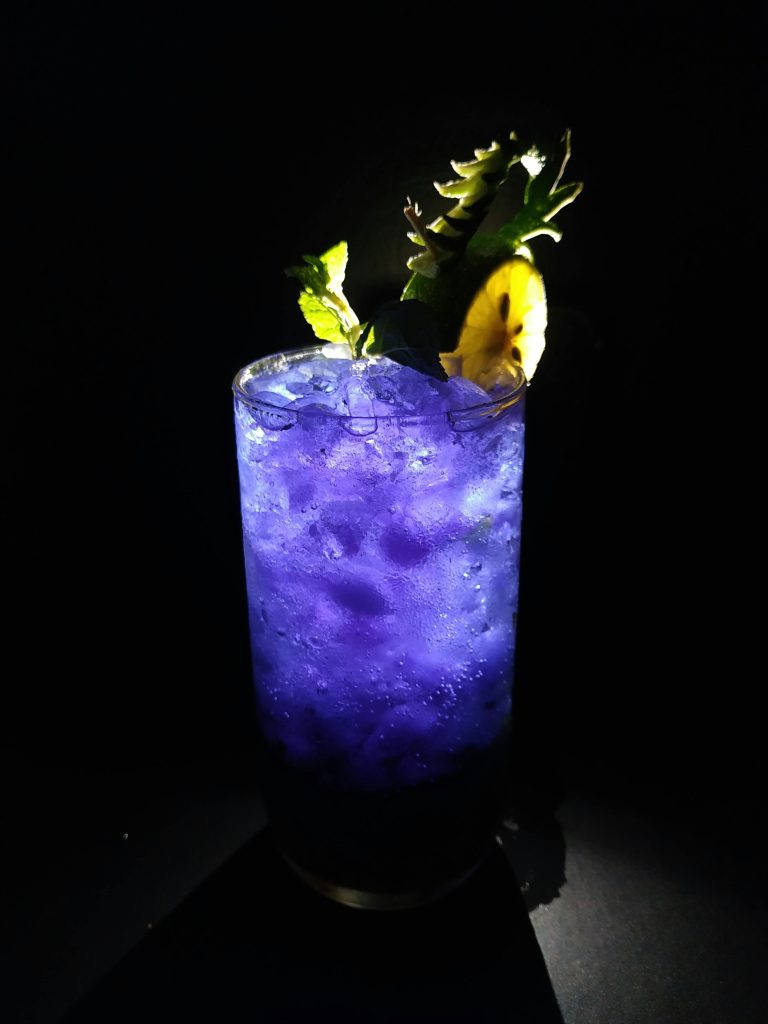 Refreshing blue mocktail avec glace et garniture d'ananas sur fond noir