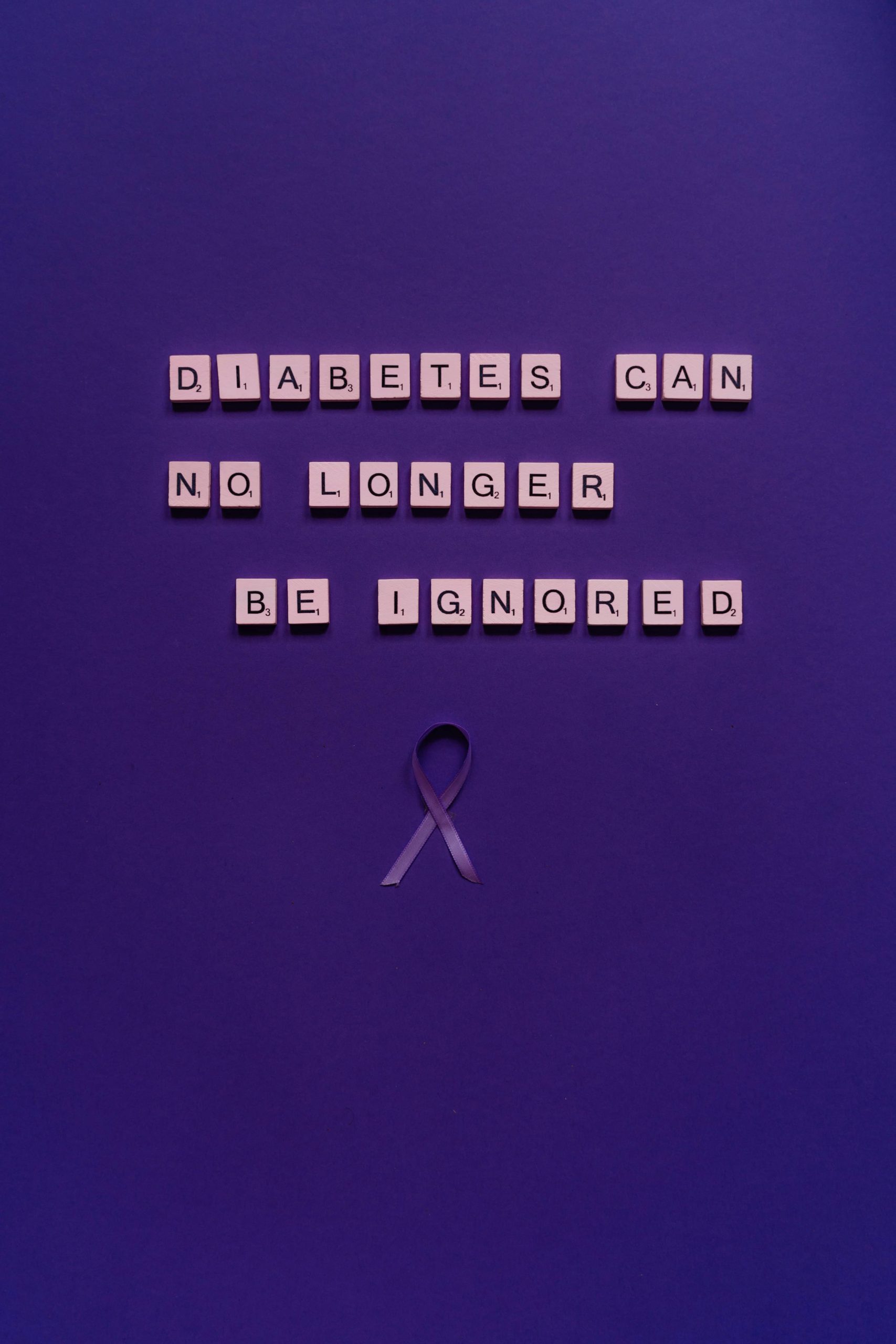 Scrabble formant un message de sensibilisation au diabète sur un fond violet avec un ruban