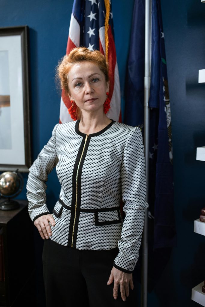 Une femme professionnelle posant avec des drapeaux dans un bureau.