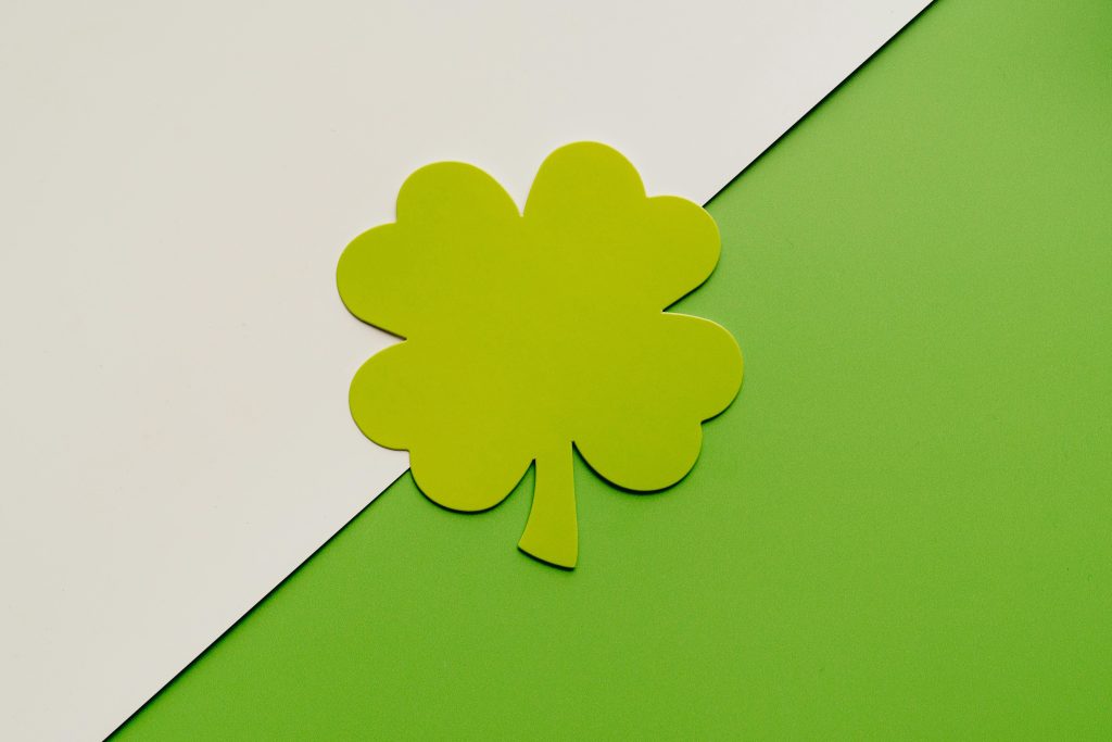A simple, minimalist four leaf clover design on a green and white background, perfect for festive themes. Un design de trèfle à quatre feuilles simple et minimaliste sur un fond vert et blanc, parfait pour des thèmes festifs.