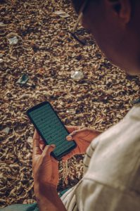 Caucasien lisant le Coran sur son téléphone en extérieur entouré de feuilles