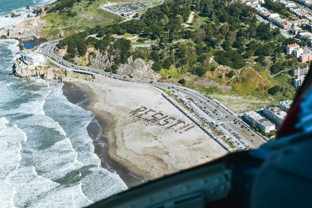 Aérienne photo capturant une grande manifestation avec le mot "RÉSISTER" écrit sur une plage, illustrant la solidarité communautaire.
