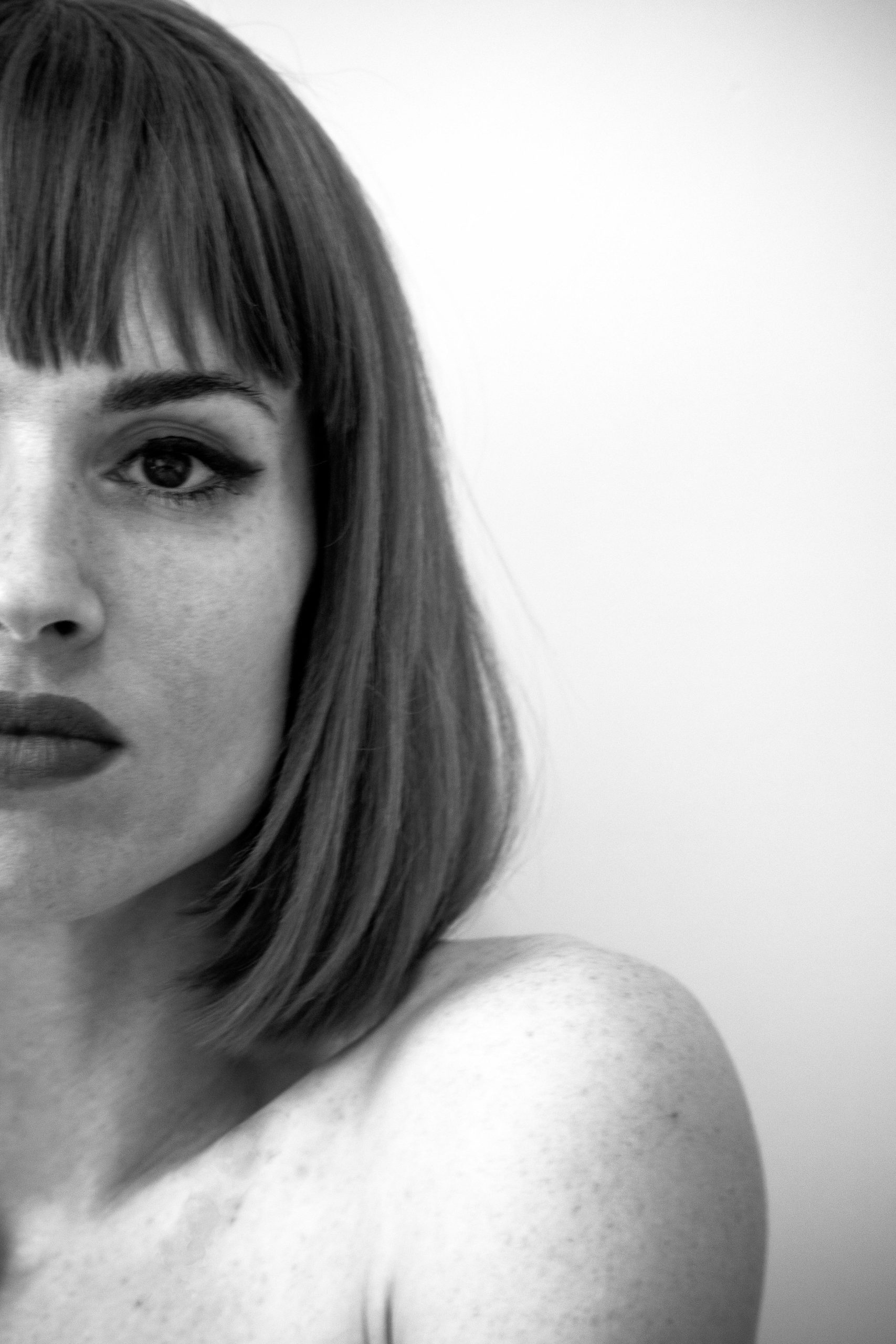 Portrait en noir et blanc d'une femme avec une frange et une coupe de cheveux bob, regardant directement l'objectif.