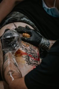 Gros plan d'un tatoueur créant un tatouage de dragon dans un studio.