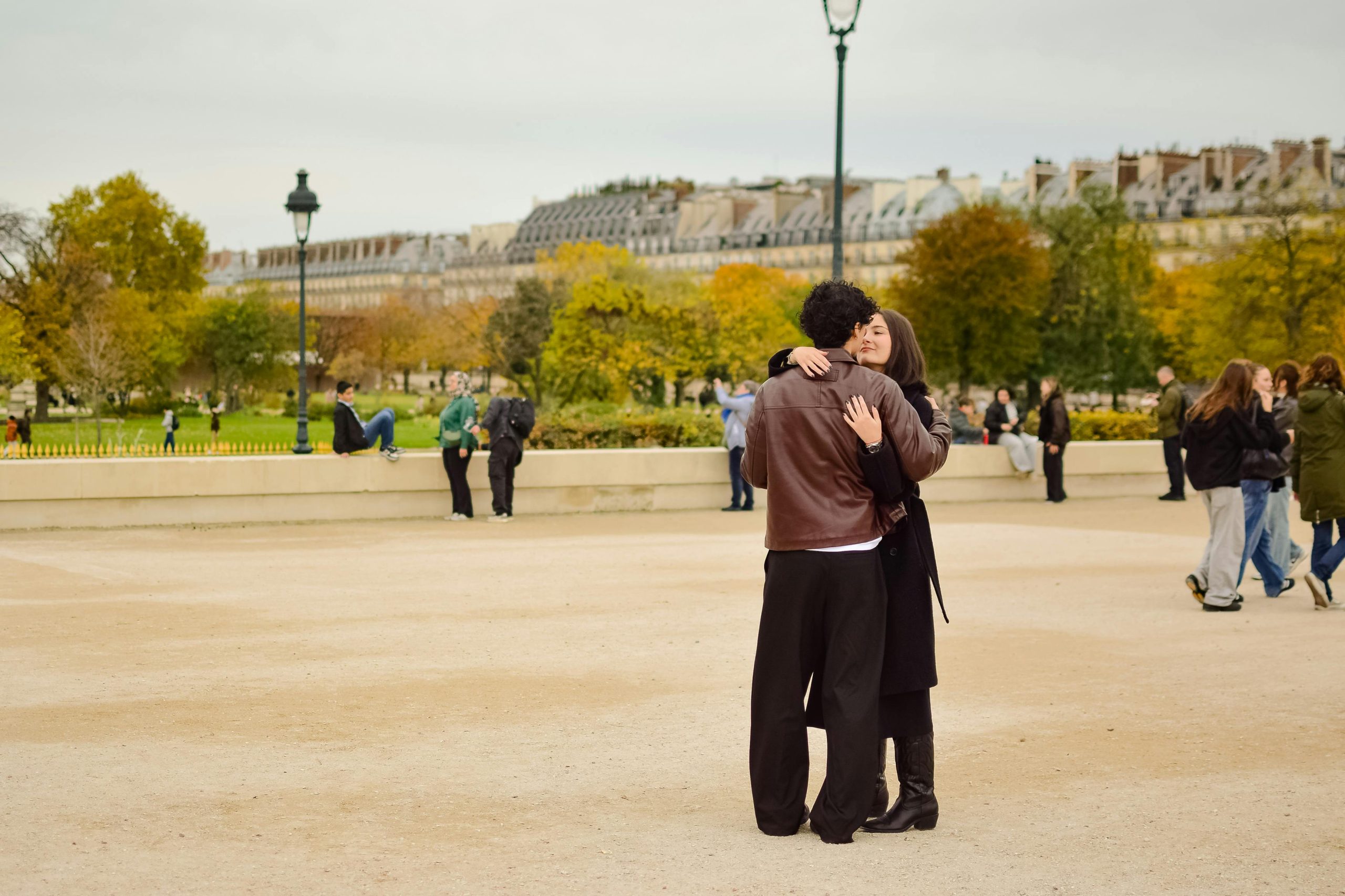 Couple partageant une étreinte amoureuse dans un magnifique parc parisien entouré de feuillage d'automne.