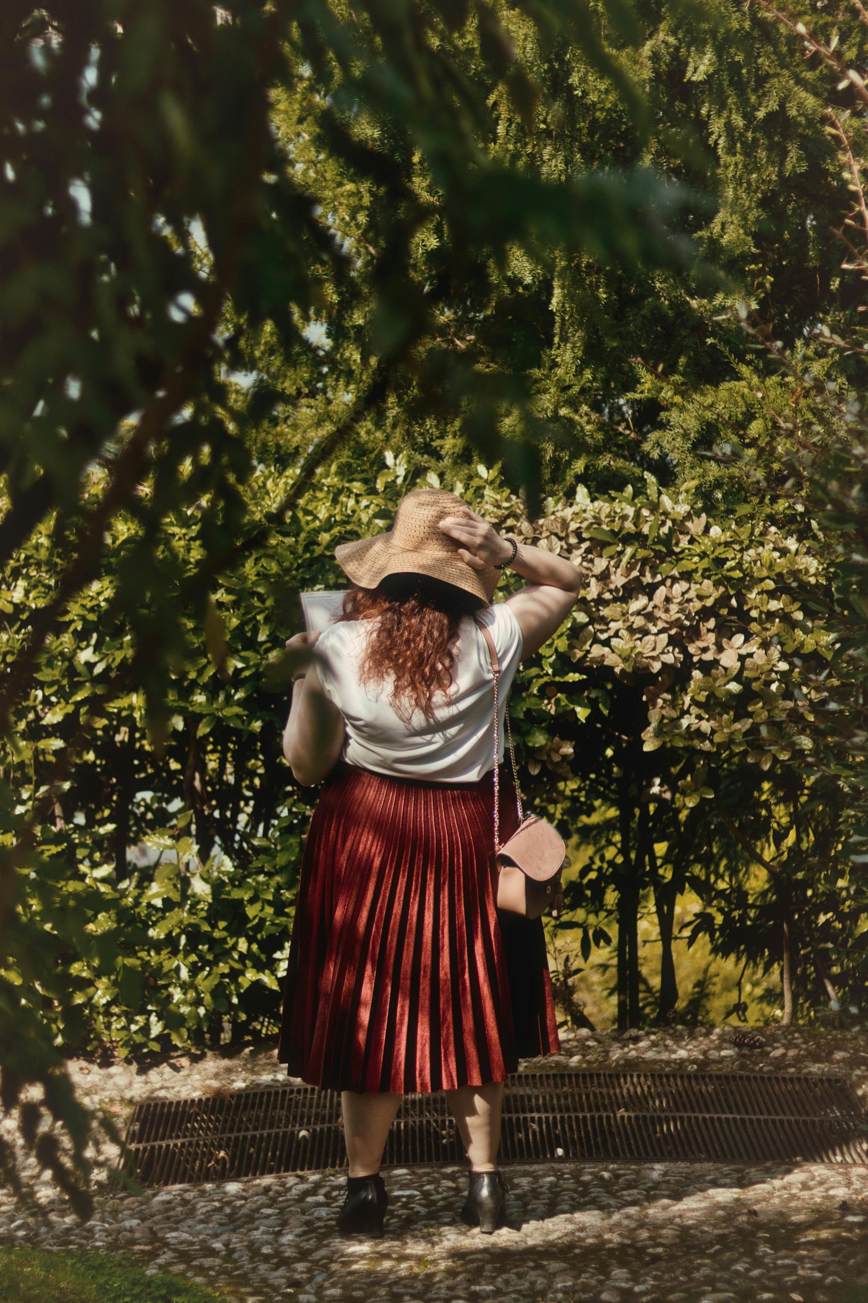 Une femme avec un chapeau de soleil et une jupe rouge profitant d'une journée ensoleillée dans un parc verdoyant.