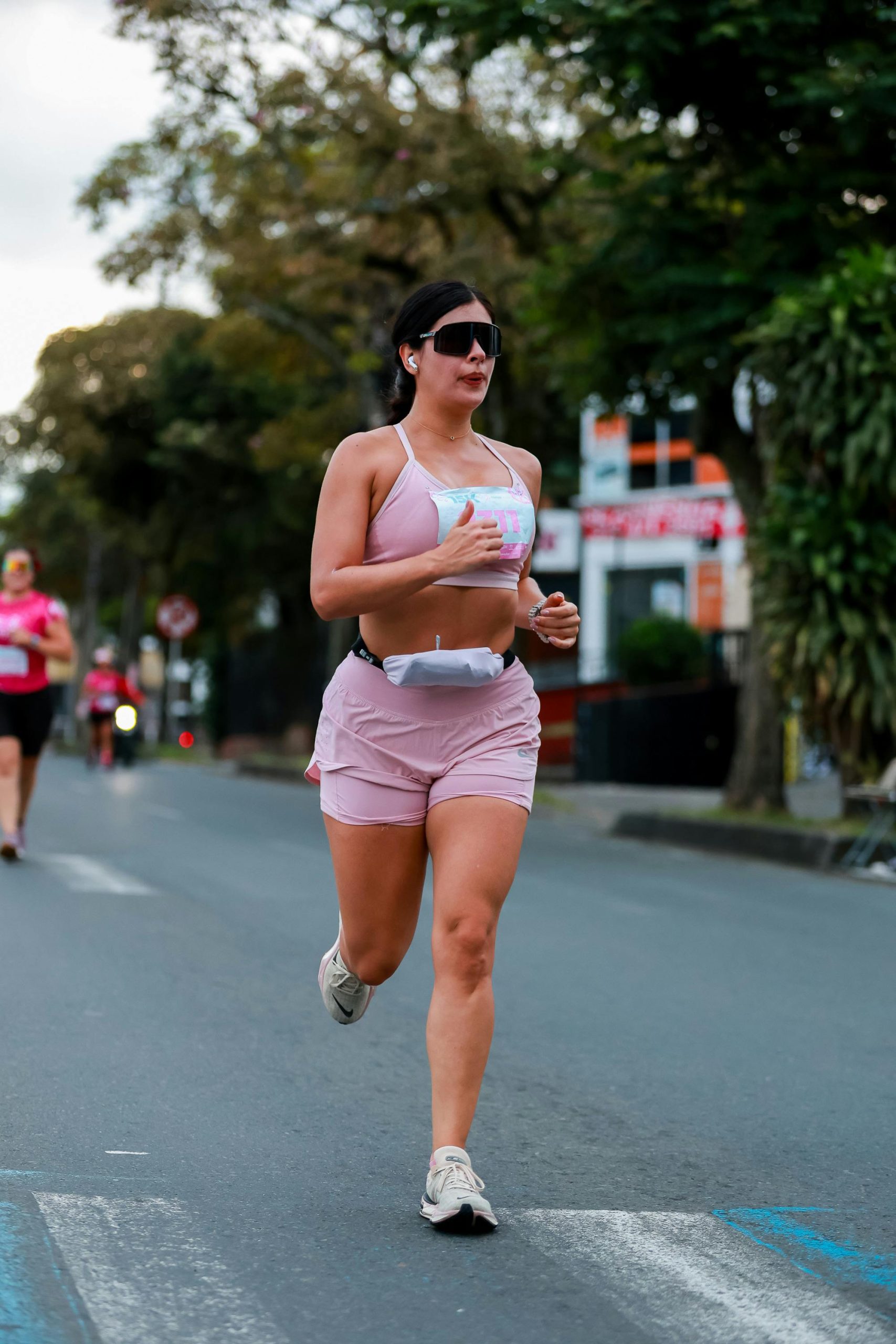 Une femme courant dans un marathon en milieu urbain. Concentrée et déterminée.