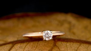 Gros plan d'une bague en diamant délicatement posée sur une feuille d'automne sèche, alliant élégance et simplicité.