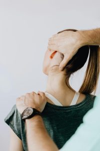 Back view of crop faceless chiropractor in wristwatch stretching neck of unrecognizable female patient during medical examination in doctor office in clinic Vue arrière d'un chiropraticien sans visage avec une montre-bracelet étirant le cou d'une patiente féminine méconnaissable lors d'un examen médical au cabinet du médecin en clinique