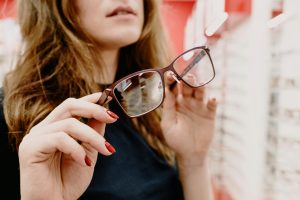 Femme cliente recadrant des lunettes à monture stylisée dans un salon optique