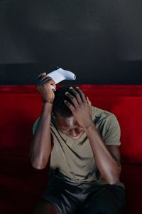Man showing frustration with a video game console indoors. Un homme montrant sa frustration avec une console de jeu vidéo à l'intérieur.