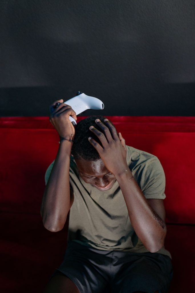 Man showing frustration with a video game console indoors. Un homme montrant sa frustration avec une console de jeu vidéo à l'intérieur.