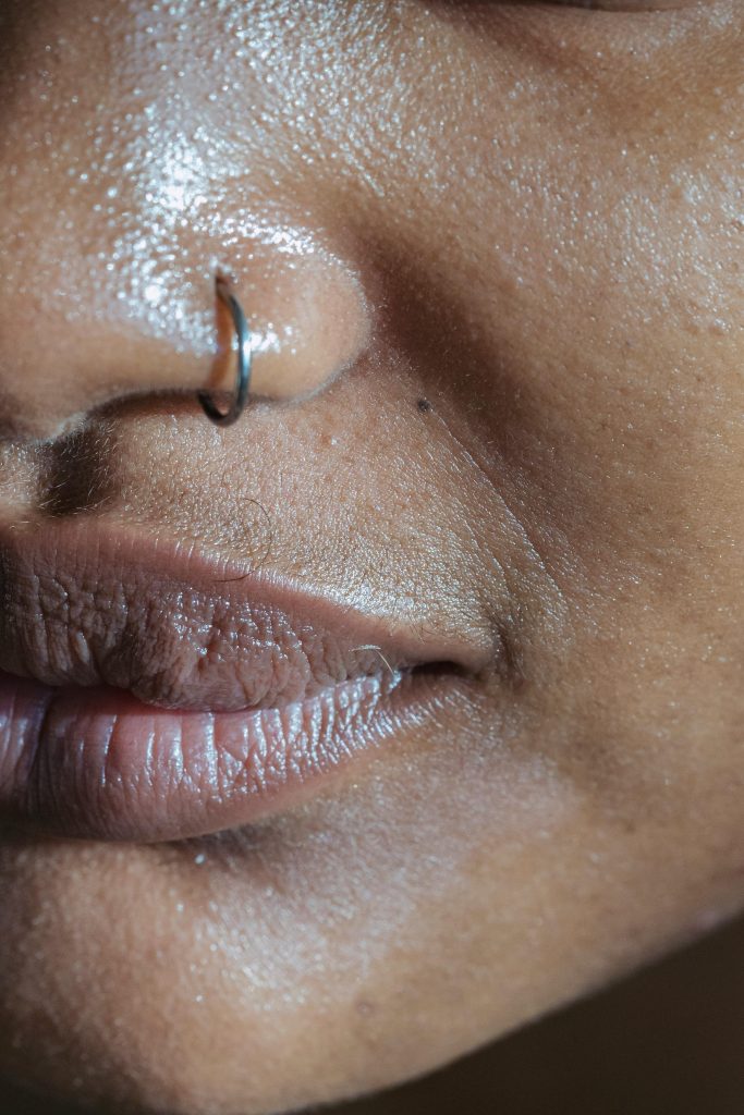 Gros plan détaillé des lèvres et du nez présentant un piercing au nez, mettant l'accent sur la texture de la peau.