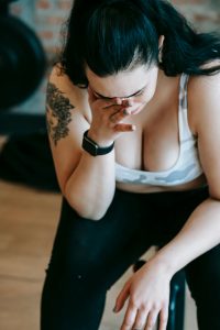 High angle of upset overweight female in sportswear wiping tears while crying in sports club Vue de haut d'une femme en surpoids contrariée en tenue de sport s'essuyant les larmes en pleurant dans un club de sport