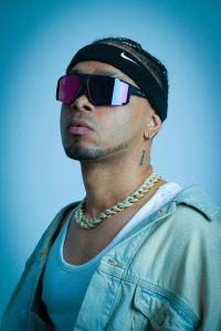 A modern portrait of a stylish music artist wearing sunglasses and a chain, exuding urban vibes. Un portrait moderne d'un artiste musical élégant portant des lunettes de soleil et une chaîne, dégageant des vibrations urbaines.