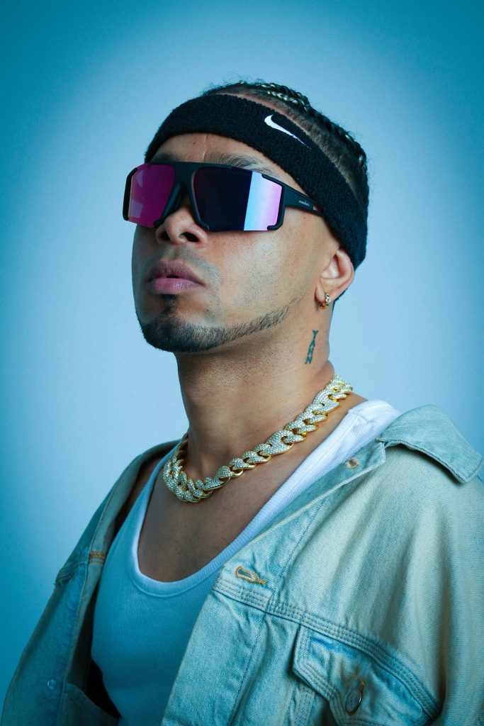 A modern portrait of a stylish music artist wearing sunglasses and a chain, exuding urban vibes. Un portrait moderne d'un artiste musical élégant portant des lunettes de soleil et une chaîne, dégageant des vibrations urbaines.