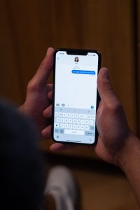 Close-up of hands texting on a smartphone indoors, showcasing modern communication. Gros plan des mains envoyant des SMS sur un smartphone à l'intérieur, mettant en avant la communication moderne.