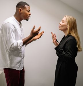 A couple engaged in a heated argument indoors, expressing strong emotions and gestures. Un couple engagé dans une dispute animée en intérieur, exprimant des émotions et des gestes forts.