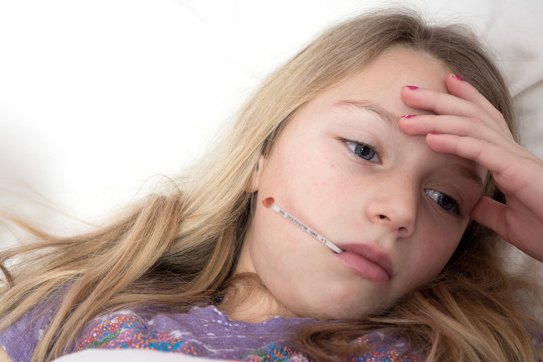 Adolescente au lit avec un thermomètre, fièvre