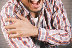 Homme se tenant le bras avec une douleur au coude