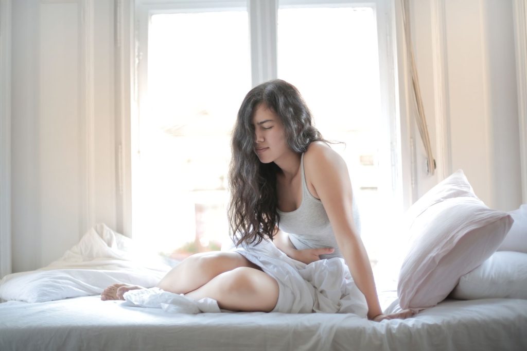 Jeune femme allongée, main sur le ventre, fatiguée