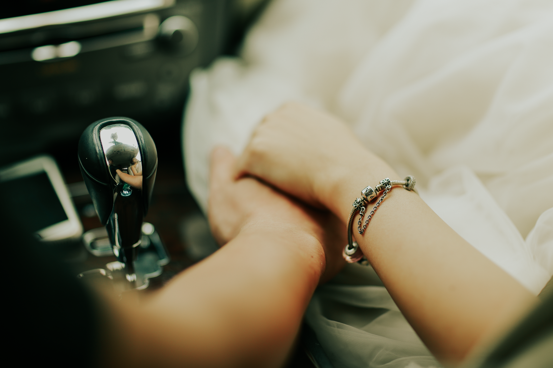 Mains d'un couple enlacées en voiture