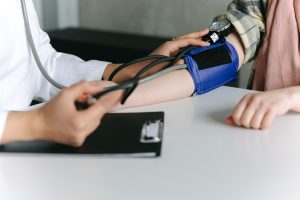 A healthcare worker uses a sphygmomanometer to check a patient's blood pressure in a medical office. Un agent de santé utilise un sphygmomanomètre pour vérifier la tension artérielle d'un patient dans un cabinet médical.