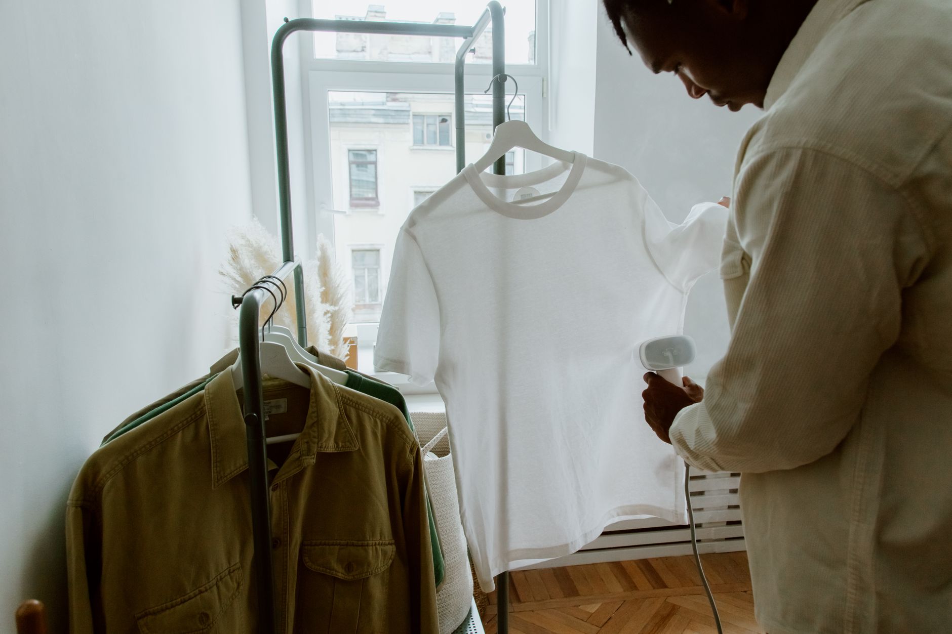 Homme repassant une chemise près d’un portant