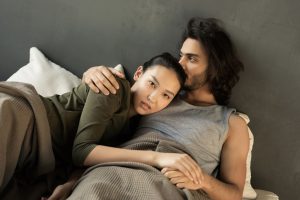 Couple enlace sur un lit dans une lumiere tamisee
