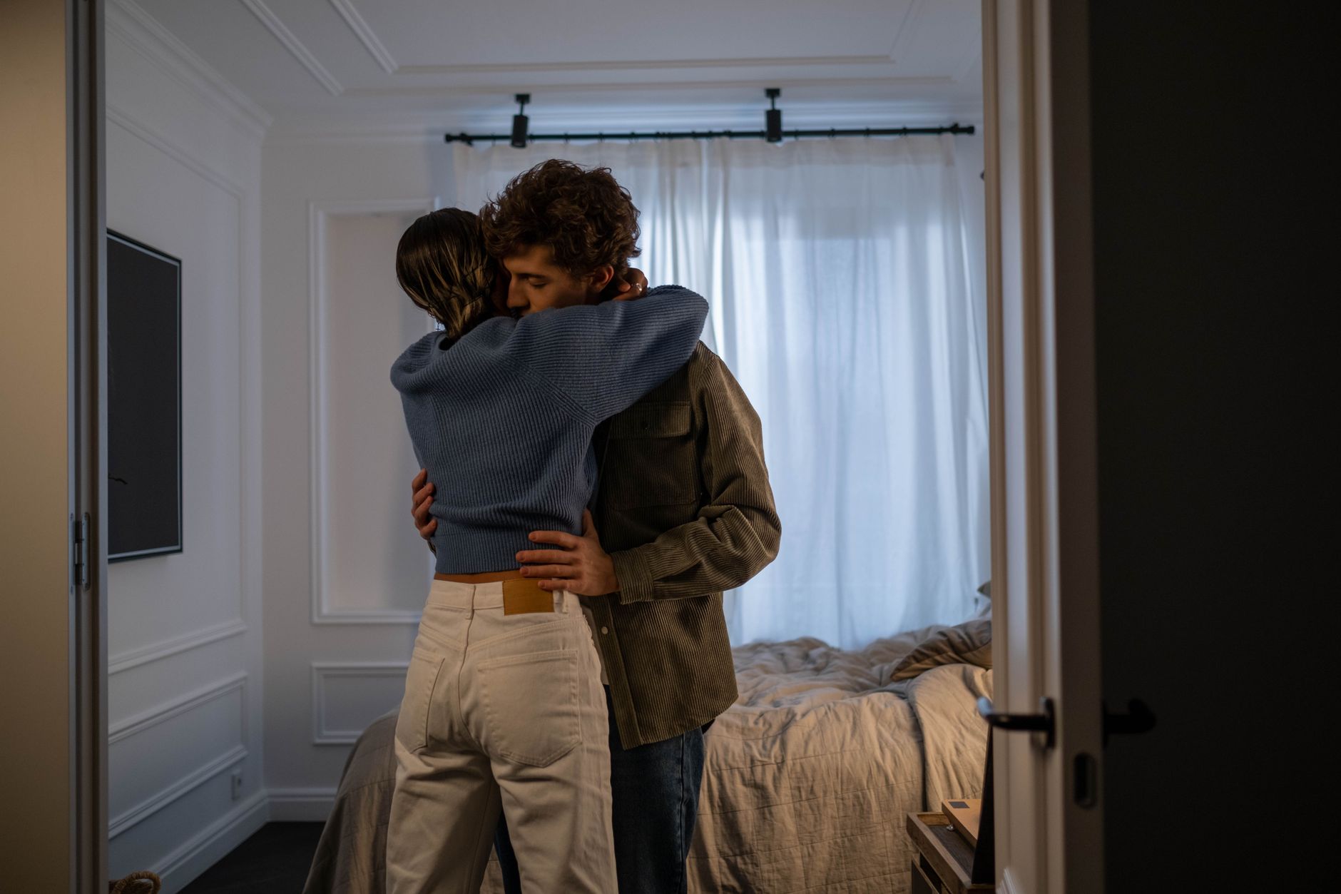 Étreinte tendre entre deux partenaires dans une chambre ensoleillée