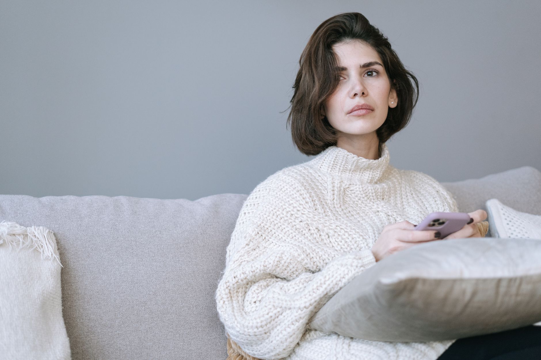 Femme distraite qui tient son téléphone sur un canapé