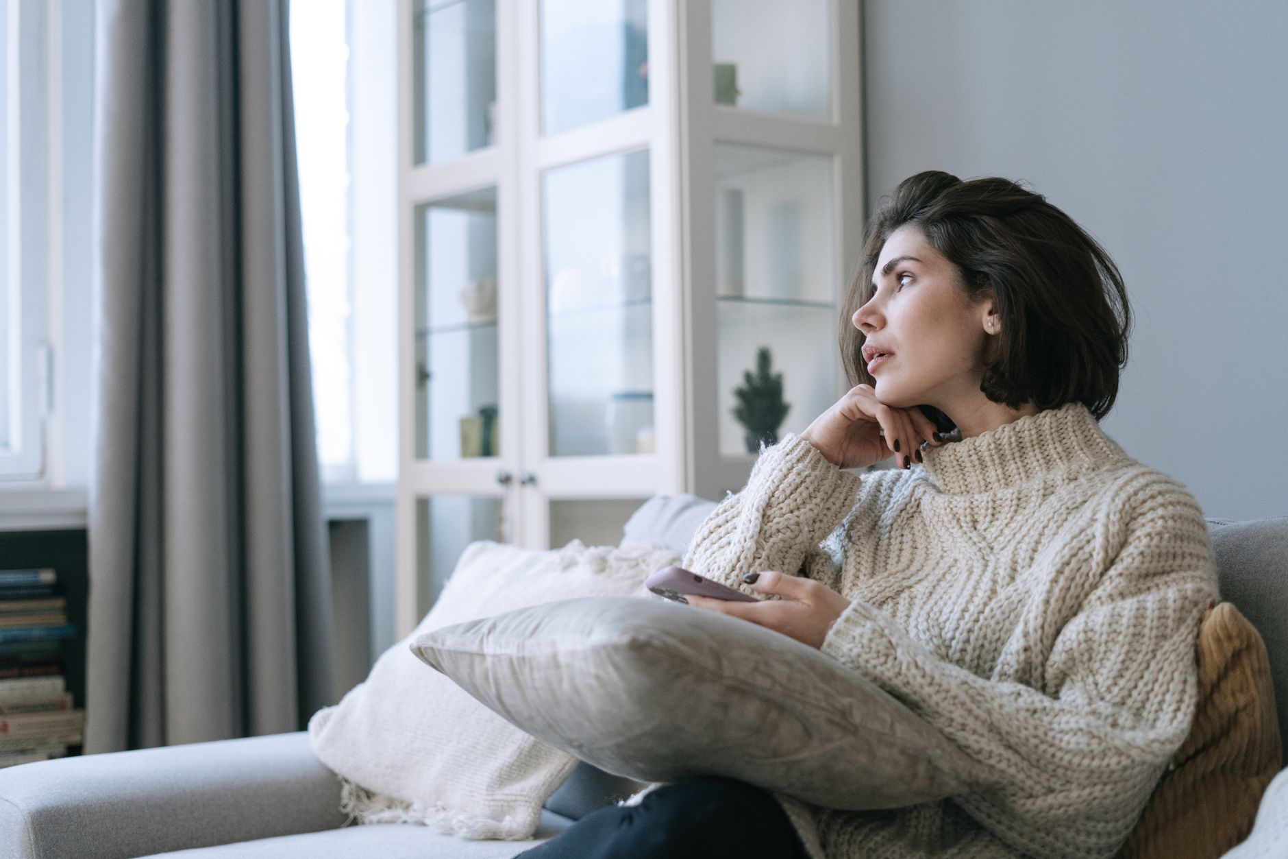 Femme pensive assise avec son téléphone dans les mains