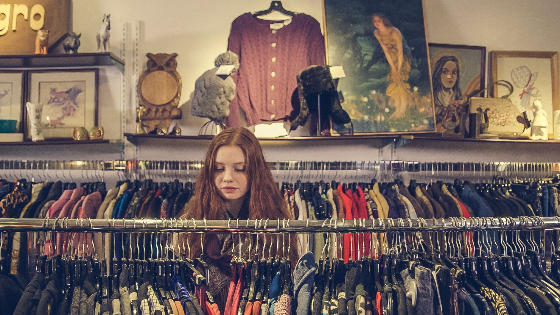 Jeune femme devant un portant de vetements en boutique