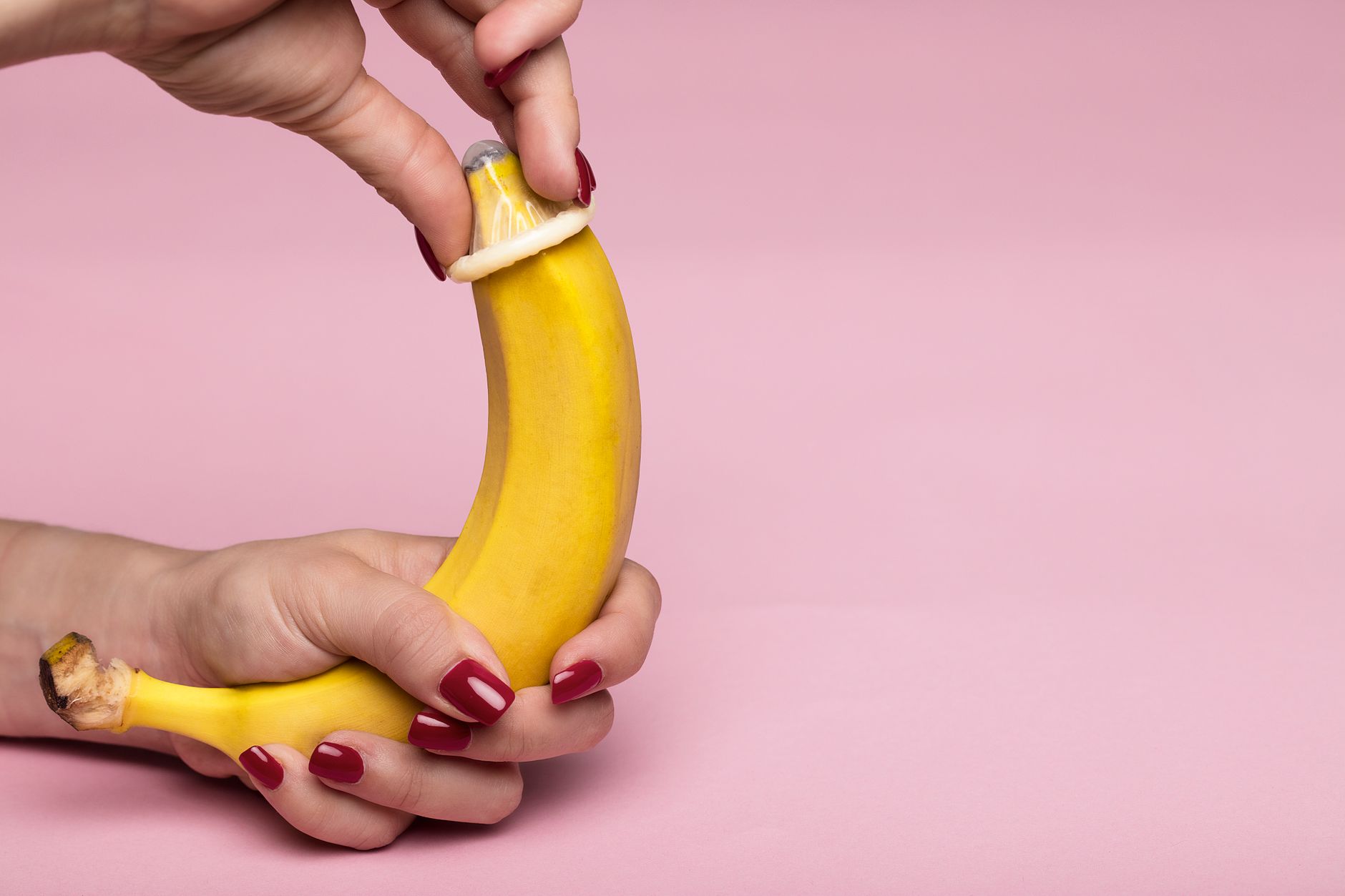 Mains posant un préservatif sur une banane