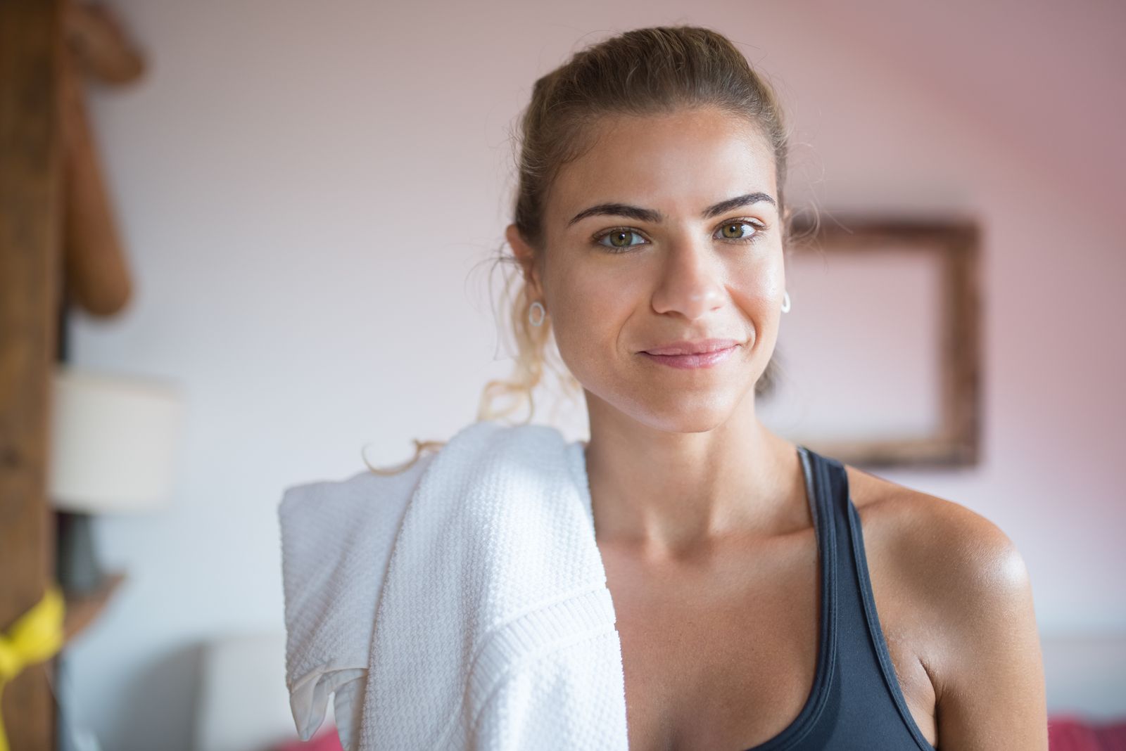 femme souriante après une séance de sport, serviette sur l'épaule